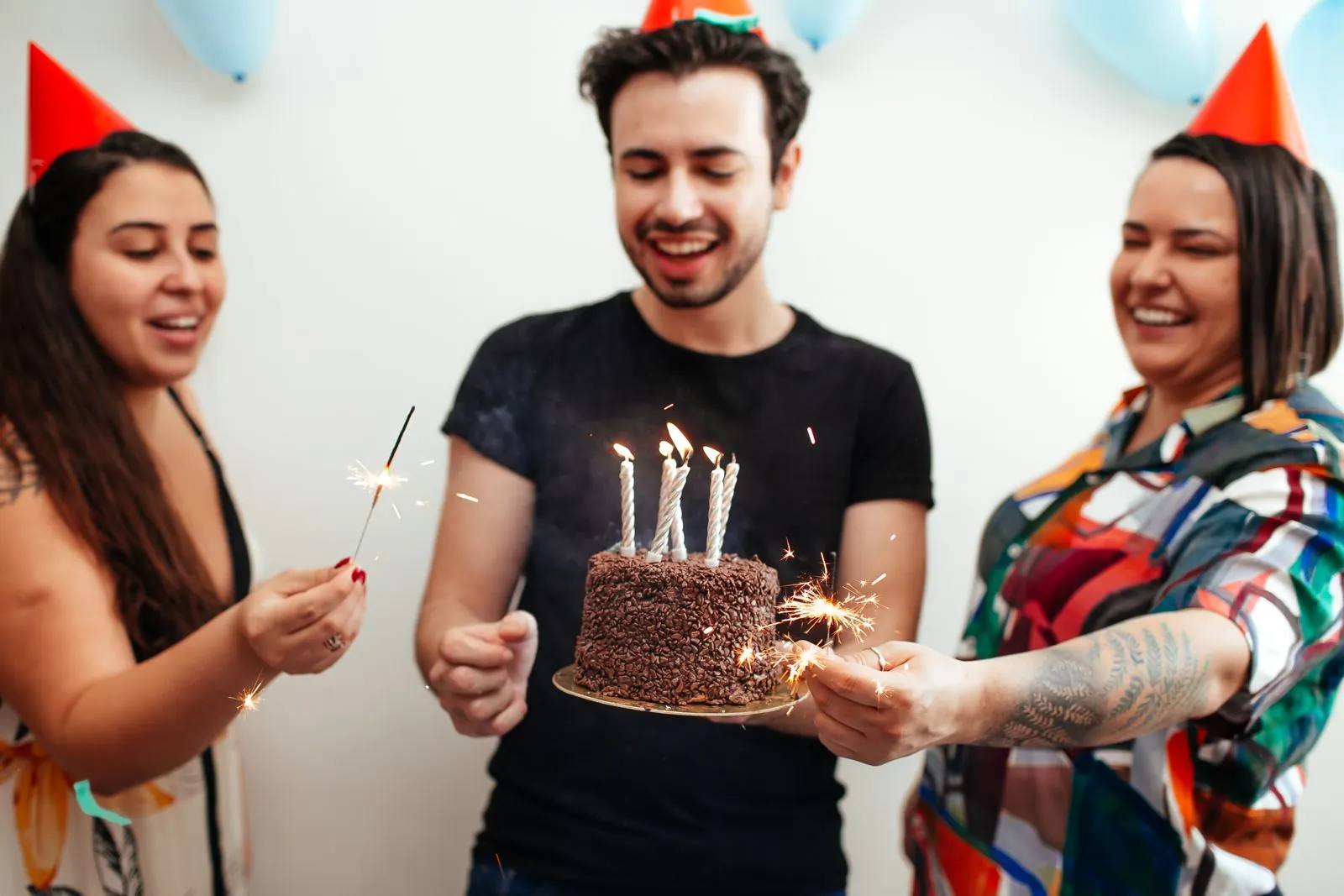 Friends celebrating a birthday party with cake and a photo booth