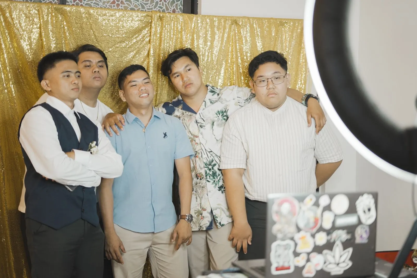Friends posing at an open-air photo booth with a ring light and gold sequin backdrop