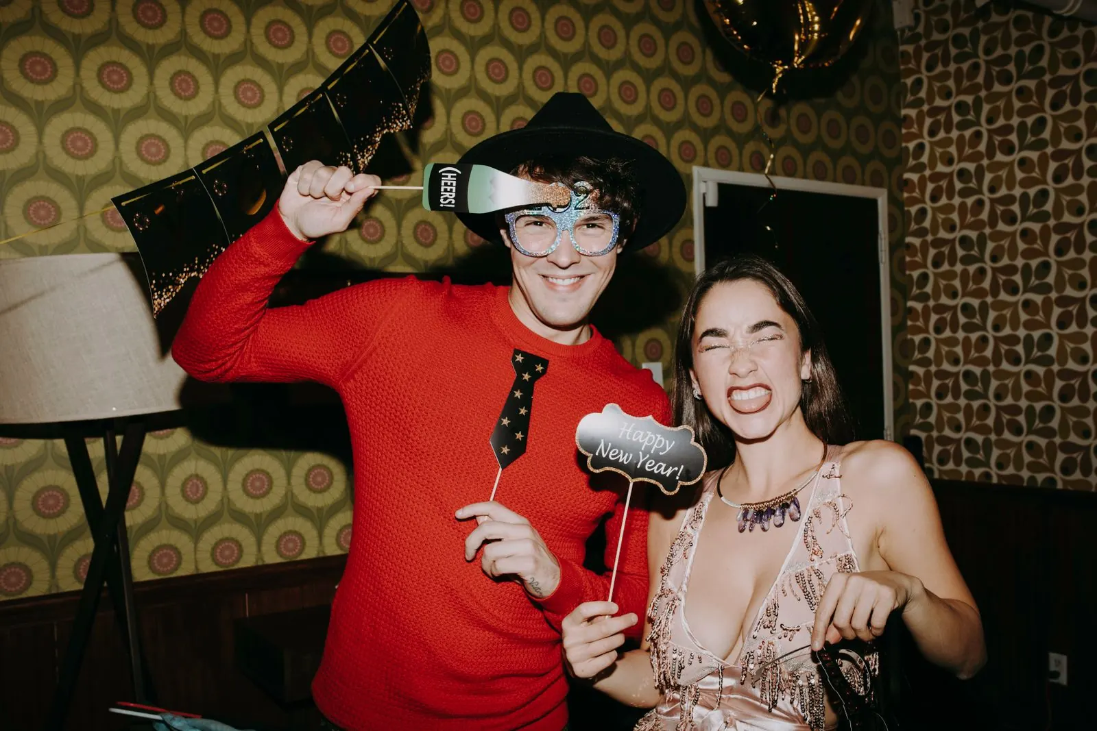 Couple posing with props at a photo booth rental during a party